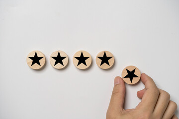 Fototapete - Hand holding black star which print screen on round wooden to give five stars for excellent evaluate after customer use product service , ISO and quality standard certificate concept.