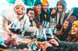 © Davide Angelini - Happy multiracial friends toasting red wine at restaurant terrace - Group of young people wearing winter clothes having fun at outdoors winebar table - Dining life style and friendship concept