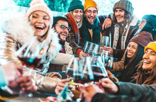 Happy Multiracial Friends Toasting Red Wine At Restaurant Terrace - Group Of Young People Wearing Winter Clothes Having Fun At Outdoors Winebar Table - Dining Life Style And Friendship Concept