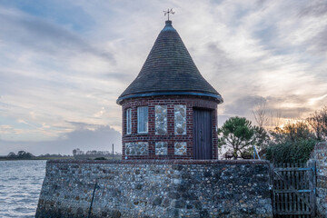 Wall Mural - the round tower overlooking the harbour at Bosham West Sussex England with the sun setting and the sea in the background