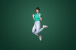 © Strelciuc - Full body photo of crazy funky woman jump up in air making horned signs screaming isolated on green color background