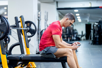 Strong athlete using cell phone in gym