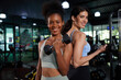 © offsuperphoto - young athletic women smiling and lifting dumbbell in the gym