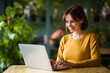© Prostock-studio - Young woman working on laptop while sitting at cafe