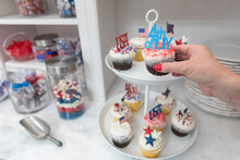 Female Hand Takes Fourth Of July Themed Cupcakes Off Display Plate