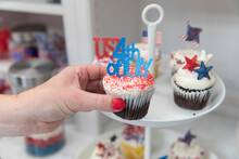 Female Hand Taking Fourth Of July Themed Cupcakes Off Display Plate