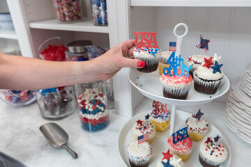 Wall Mural - Female hand takes Fourth of July themed cupcakes off display plate