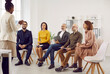 © Studio Romantic - Female business coach speaks in front of small group of business people teaching them new business knowledge. Satisfied different people sitting on chairs in row and listening to dark skinned woman.
