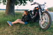 © Cavan Images - Young woman with a cigarette sitting near a motorcycle