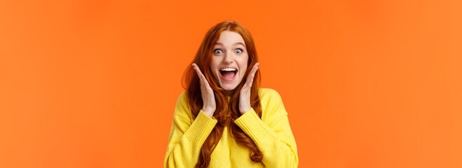 Wall Mural - Excitement, emotions and holidays concept. Waist-up shot cheerful impressed and excited redhead woman screaming from thrill and joy, hold hands near face, open mouth and glance amazed