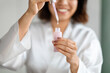 © Prostock-studio - Cropped of young woman using face serum at home