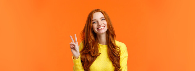 waist-up cheerful gorgeous redhead woman with long curly red hair, showing peace sign and smiling ha