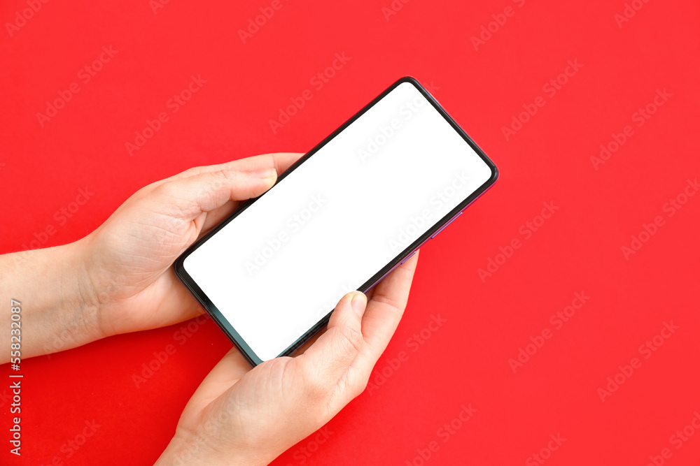 Female hands with modern mobile phone on red background, closeup