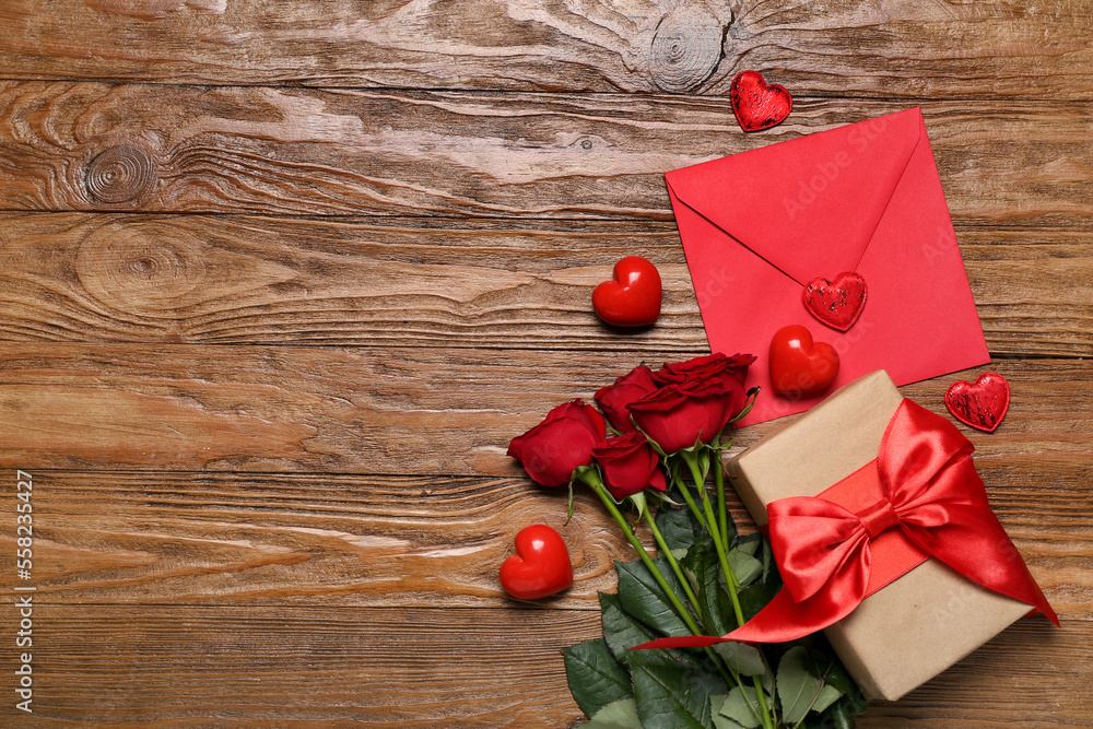 Red roses, envelope, gift and hearts on wooden background. Valentine's Day celebration