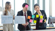 © Bangkok Click Studio - Asian professional successful female businesswoman employee in formal suit standing explaining brainstorming pointing data information on sticky note on glass board to colleagues in meeting room