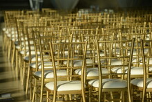 Gold Colored Chairs In Rows At Wedding Reception 