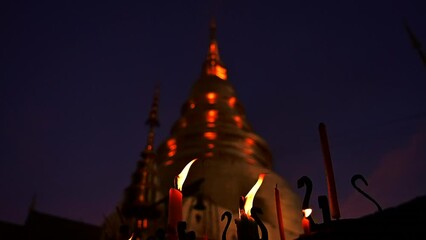 Wall Mural - Slow motion video of candle burning with golden pagoda background.