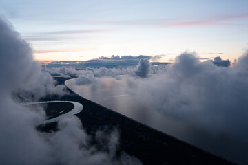 Canvas Print -  an aerial view of a river surrounded by clouds and a sky with a sunset in the background and a few clouds in the foreground with a river running through the center of the image.