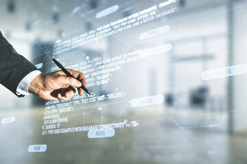 Wall Mural - male hand with pen working with abstract virtual coding concept on blurred office background. multie