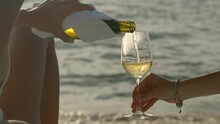 Close Up Shot Of White Wine Pouring Into The Glass On The Beach Near The Ocean Outdoors
