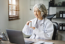 Caring Asian Therapist Conducts Video Consultation, Communicates With Patient Via An Online Conference, Uses Laptop, Diagnoses, Recommended And Prescribed Medications, And Also Answers Questions.