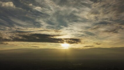 Wall Mural - Time lapse video of the sun setting behind some mountains during a cloudy day.