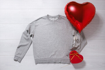Grey sweatshirt mockup. Valentines Day concept shirt, balloon heart shape on wooden background. Copy space, template blank front view clothes. Romantic outfit. Flat lay holiday fashion