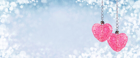 Two Pink red sparkling crystals heart pendants, valentine day greeting card. Bokeh blue abstract background. Valentines Day card or winter wedding wide web banner. Couple love