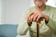 © sorapop - Hands of Asian Old man sitting resting at home hold wooden walking cane, Elderly hand holding handle of cane, senior disabled man holding walking stick, retirement medical healthcare concept