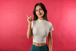 Cute brunette woman wearing white ribbed crop isolated over red background shaking index finger and grimacing hesitant, have suggestion or worry, saying her opinion, judging awkward situation.