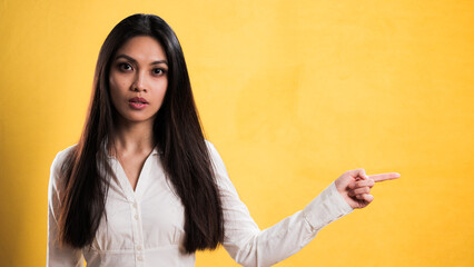 Wall Mural - Young pretty woman points to something - studio photography