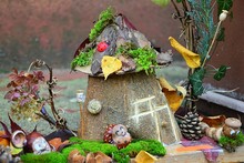 Decorative Handmade House Surrounded By Figures Of Animals - Hedgehog, Rabbit, Caterpillar,  Made Of Chestnuts And Acorns, Displayed As Autumn Outdoor Decoration.