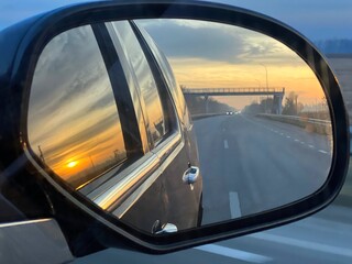 Sunset road reflection in the car mirror. 