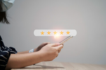 Wall Mural - Woman using smartphone for select five stars for client evaluation and customer satisfaction after use product and service concept.