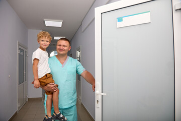 Advertising of a children's hospital, where doctors carefully take care of young patients, are carried on their hands. A caring doctor brings the boy in his arms to the treatment room for examination