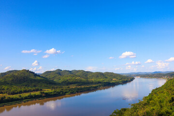 Beautiful natural scenery of river in tropical green forest with trees on two sides and mountain in background