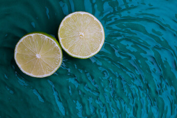 Wall Mural - Citrus fruits in green water background with concentric circles and ripples. Refreshing summer concept,