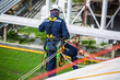 © chitsanupong - Top view male worker inspection wearing safety first harness rope safety line working at a high place on tank roof spherical gas