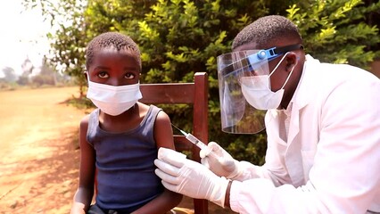 an african doctor injects the vaccine to a child. coronavirus protection in africa concept.