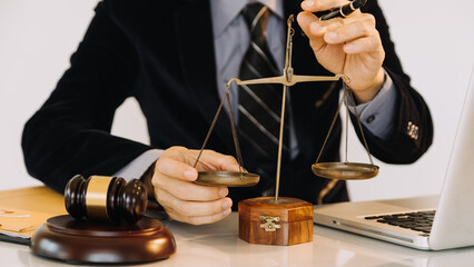 Business and lawyers discussing contract papers with brass scale on desk in office. Law, legal services, advice, justice and law concept.