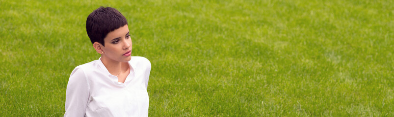 Wall Mural - Young woman sitting on the beautiful grass in spring	