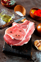 Wall Mural - Raw pork meat. Fresh steaks on slate board on black background. Top view