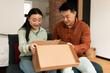 © Prostock-studio - Happy asian spouses unpacking box after successful shopping, receiving order from online store