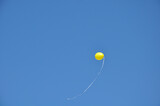 Fototapeta Tulipany - Single yellow balloon flown away in the blue sky background 