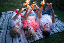Young Group Of Friends Having Fun With Sparklers In Park During Summer