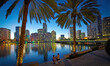 © Cavan Images - A Couple Takes Picture Of Each Other On A Waterside Park Bench With Views Of Miami At Sunset