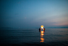 Two People In Release Paper Lantern From Lake