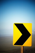 A Yellow Caution Arrow Sign Along The Road.