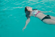 © Cavan Images - Relaxed girl with swimsuit lying in the pool water