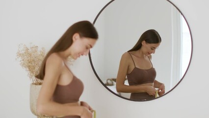 Wall Mural - Young pretty fit lady looking at mirror measuring her waist with tape, smiling to her reflection at home, free space